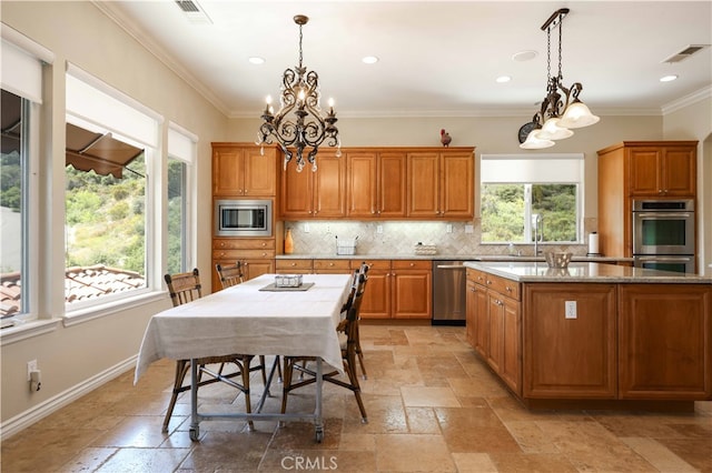 kitchen with an inviting chandelier, appliances with stainless steel finishes, hanging light fixtures, and a kitchen island