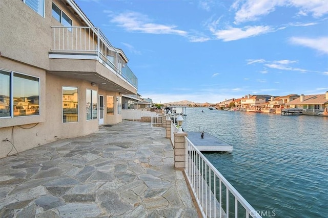 view of patio with a water view and a dock