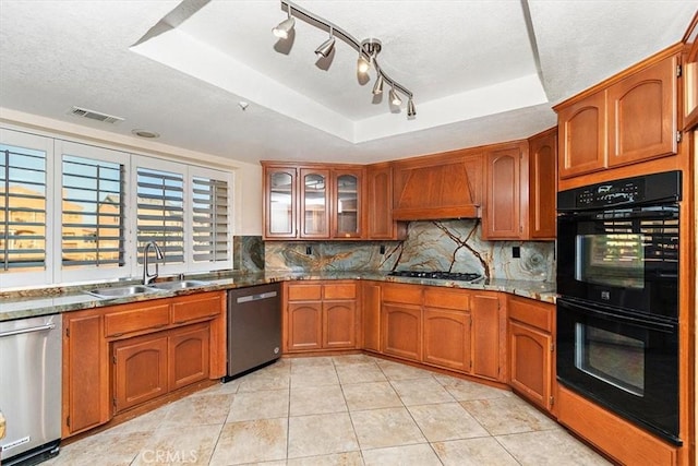 kitchen with custom exhaust hood, a raised ceiling, decorative backsplash, light stone counters, and stainless steel appliances