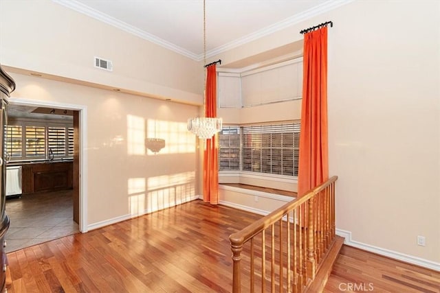 interior space with hardwood / wood-style flooring, crown molding, and a chandelier