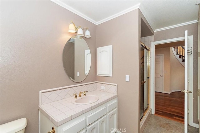 bathroom featuring ornamental molding, vanity, hardwood / wood-style flooring, toilet, and a shower with shower door