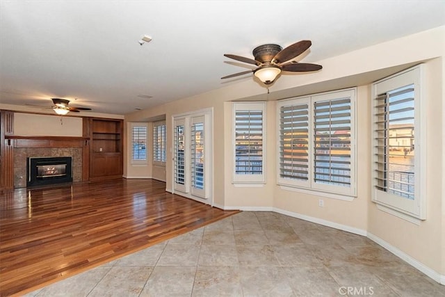 unfurnished living room with a premium fireplace, ceiling fan, and light wood-type flooring