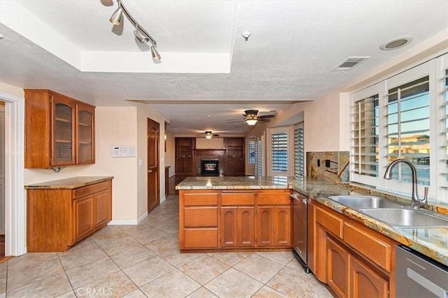 kitchen featuring a textured ceiling, dishwasher, kitchen peninsula, and sink