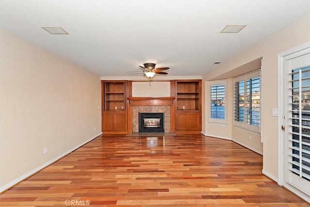 unfurnished living room with ceiling fan, light wood-type flooring, and a high end fireplace