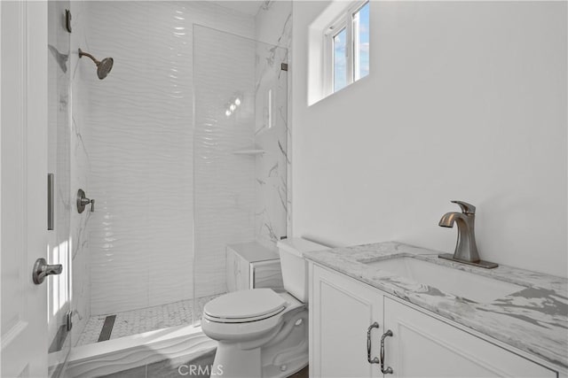 bathroom with vanity, toilet, and a tile shower