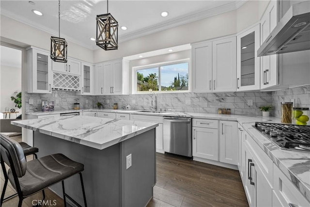 kitchen featuring sink, wall chimney range hood, a kitchen island, white cabinets, and appliances with stainless steel finishes