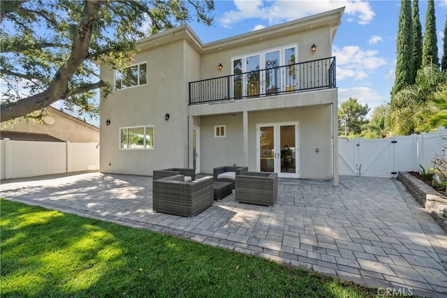 rear view of property featuring outdoor lounge area, a balcony, a patio, and french doors