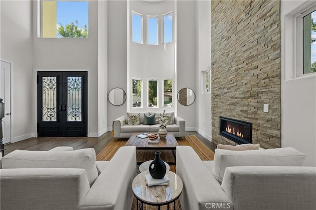 living room featuring dark hardwood / wood-style floors, a fireplace, a high ceiling, and french doors