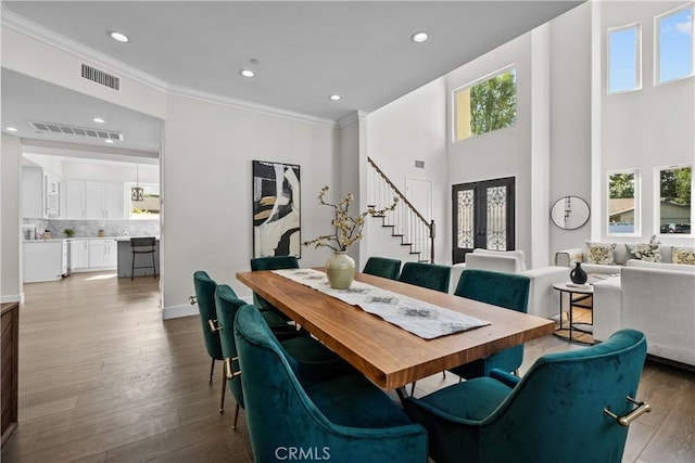 dining room with hardwood / wood-style floors, a wealth of natural light, crown molding, and a high ceiling