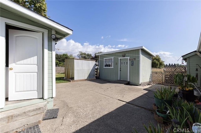 view of patio with a shed, an outdoor structure, and fence