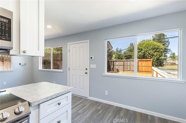 kitchen featuring wood finished floors, white cabinetry, baseboards, light countertops, and appliances with stainless steel finishes