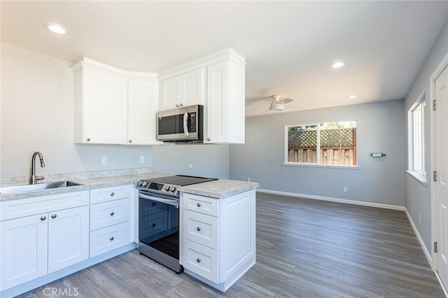 kitchen featuring white cabinetry, appliances with stainless steel finishes, a sink, and wood finished floors