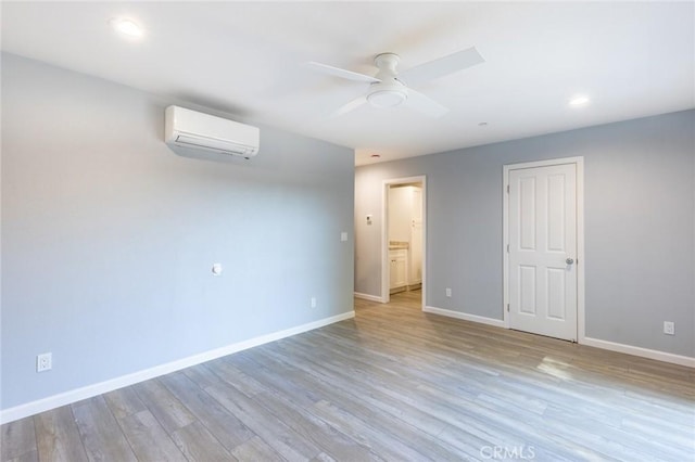 unfurnished room featuring light wood-style flooring, recessed lighting, a ceiling fan, baseboards, and a wall mounted air conditioner