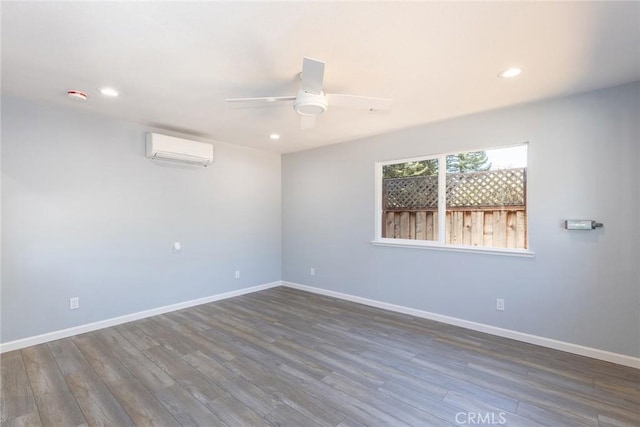 unfurnished room featuring recessed lighting, an AC wall unit, ceiling fan, wood finished floors, and baseboards