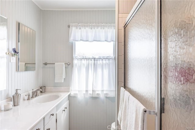 bathroom featuring a shower with shower door and vanity