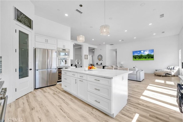 kitchen featuring light wood-type flooring, white cabinetry, hanging light fixtures, and stainless steel refrigerator