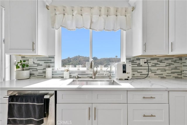 kitchen with dishwashing machine, white cabinetry, and sink