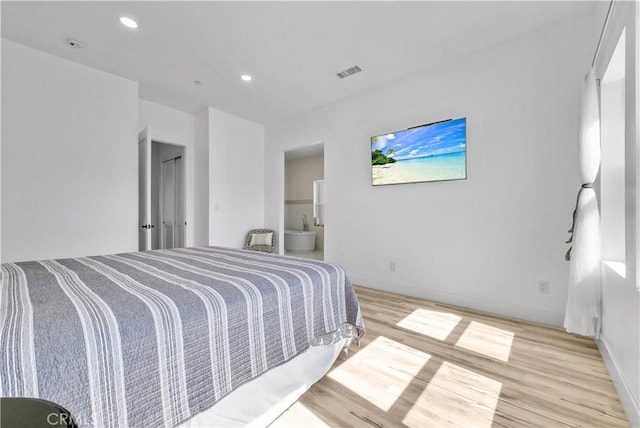 bedroom featuring ensuite bath and light hardwood / wood-style floors