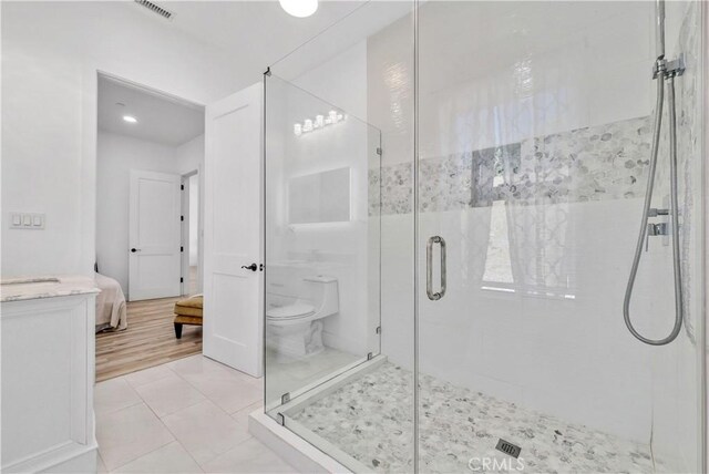 bathroom with hardwood / wood-style flooring, toilet, and a shower with door