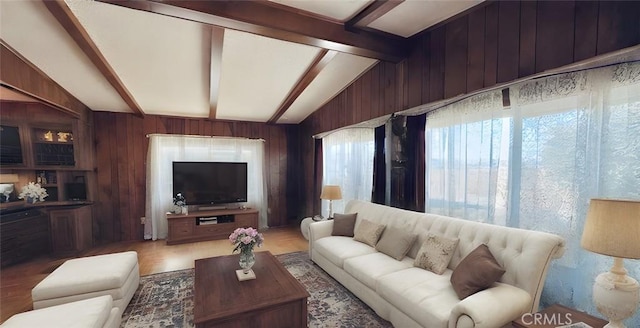 living area with vaulted ceiling with beams and wood walls