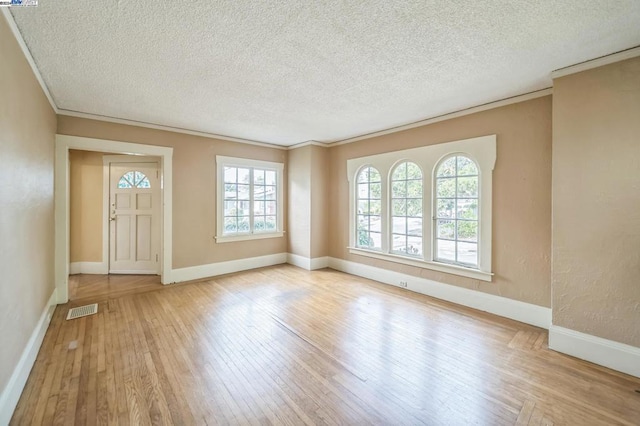 interior space with a textured ceiling, crown molding, and light hardwood / wood-style flooring