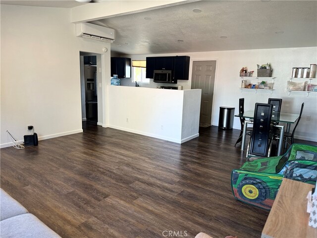 living room with a textured ceiling, dark hardwood / wood-style floors, and an AC wall unit