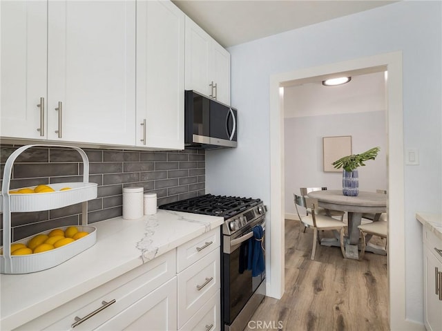 5451 W 117th St, Hawthorne, CA 90304 - kitchen featuring gas range, light wood-style flooring, white cabinets, tasteful backsplash, and light stone countertops