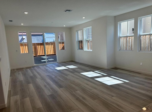 spare room with dark hardwood / wood-style flooring and plenty of natural light