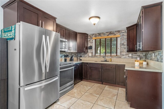 kitchen with dark brown cabinets, stainless steel appliances, sink, and tasteful backsplash