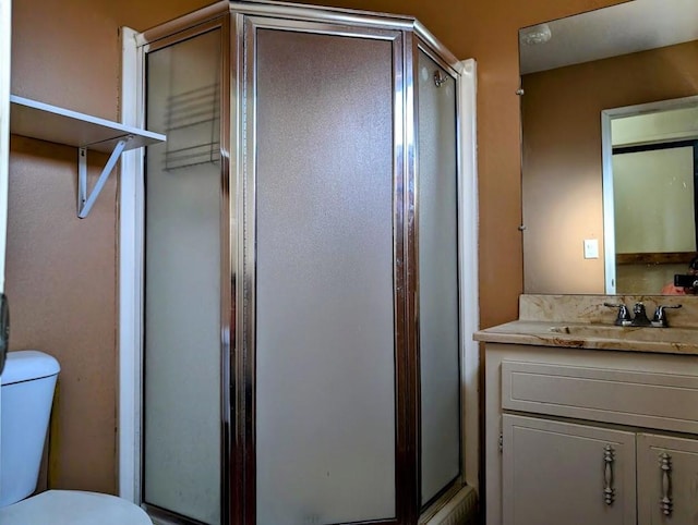 bathroom featuring a shower with door, vanity, and toilet