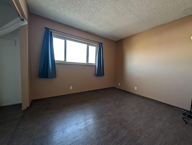 spare room featuring a textured ceiling and dark hardwood / wood-style flooring