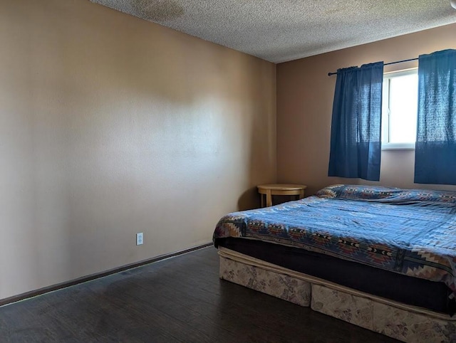 bedroom with a textured ceiling and dark hardwood / wood-style flooring