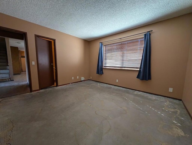 unfurnished room featuring a textured ceiling and concrete floors