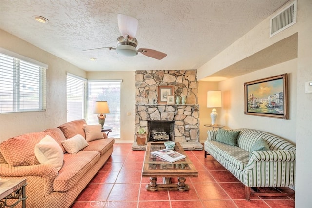 living room featuring tile patterned floors, ceiling fan, a textured ceiling, and a fireplace