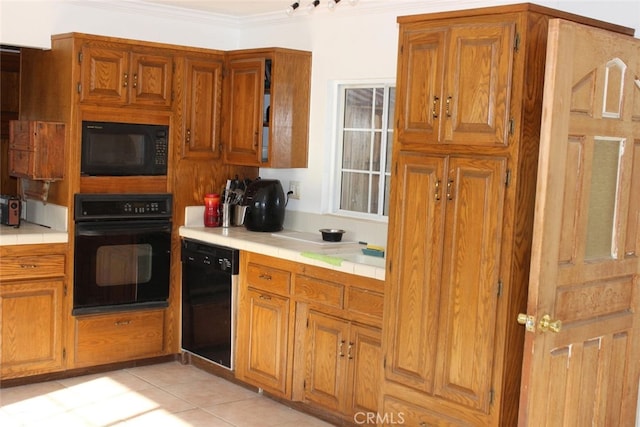 kitchen featuring tile countertops, crown molding, light tile patterned floors, and black appliances