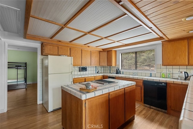 kitchen featuring black dishwasher, a kitchen island, light hardwood / wood-style flooring, tile counters, and white fridge