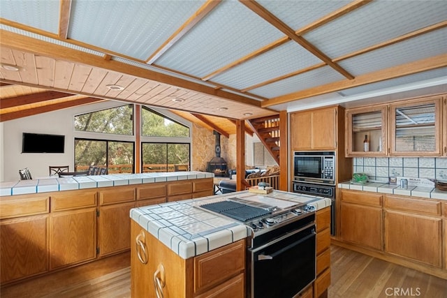 kitchen with lofted ceiling, a center island, tile countertops, and light hardwood / wood-style flooring