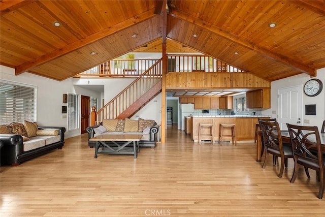 living room with high vaulted ceiling, beamed ceiling, and light hardwood / wood-style flooring