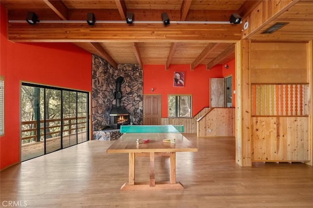 rec room featuring a wood stove, hardwood / wood-style floors, wooden ceiling, and beam ceiling