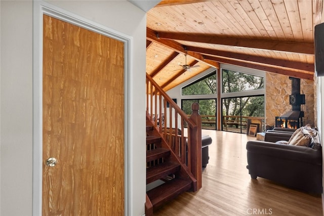 living room featuring a wood stove, hardwood / wood-style flooring, vaulted ceiling with beams, and wooden ceiling