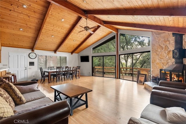 living room featuring a wood stove, ceiling fan, plenty of natural light, and light hardwood / wood-style flooring