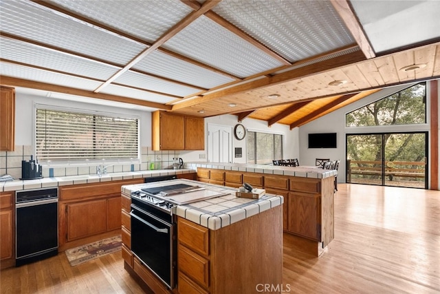 kitchen featuring lofted ceiling with beams, tile countertops, plenty of natural light, and a kitchen island