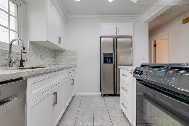 kitchen with sink, light stone counters, appliances with stainless steel finishes, white cabinets, and ornamental molding