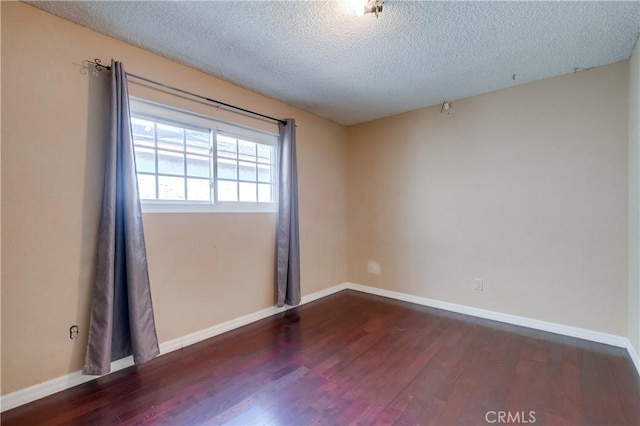 spare room with dark wood-type flooring and a textured ceiling