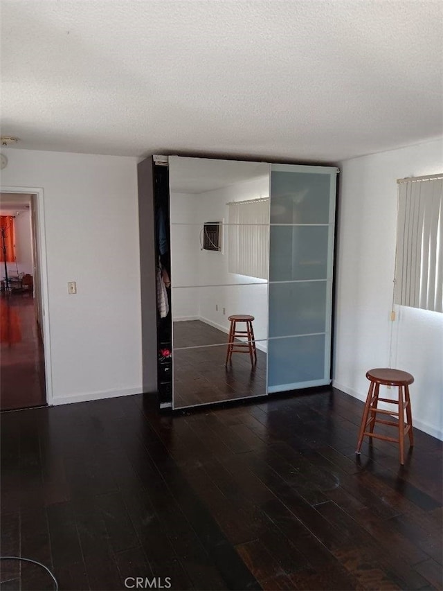 empty room featuring a textured ceiling and dark hardwood / wood-style floors