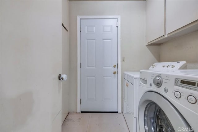 clothes washing area featuring cabinets and washer and clothes dryer