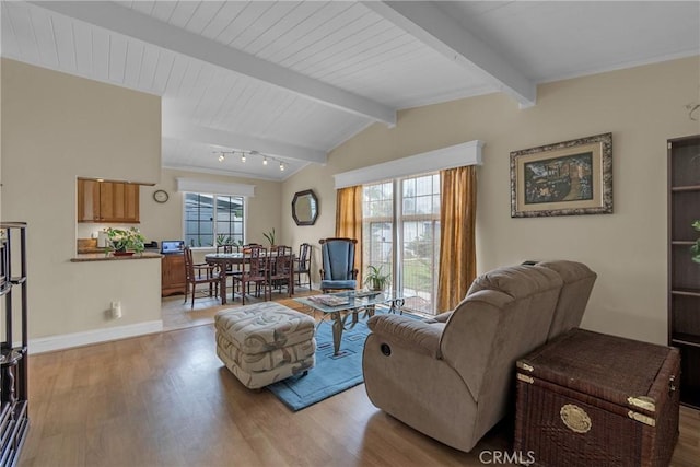 living area with baseboards, lofted ceiling with beams, and light wood-style floors