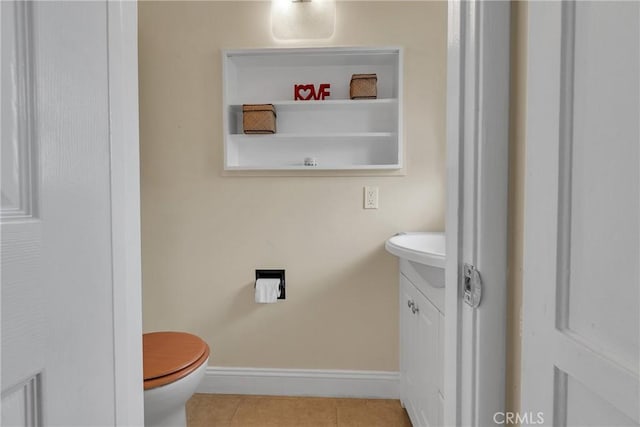 half bathroom featuring vanity, tile patterned flooring, baseboards, and toilet
