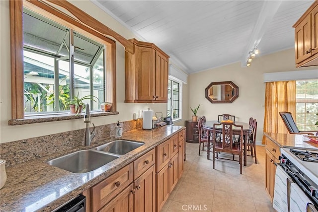 kitchen with a sink, stone counters, light tile patterned floors, and brown cabinets