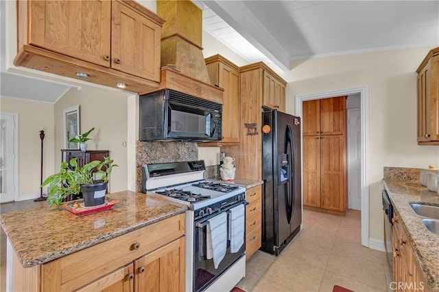 kitchen with light tile patterned flooring, light stone countertops, tasteful backsplash, a sink, and black appliances